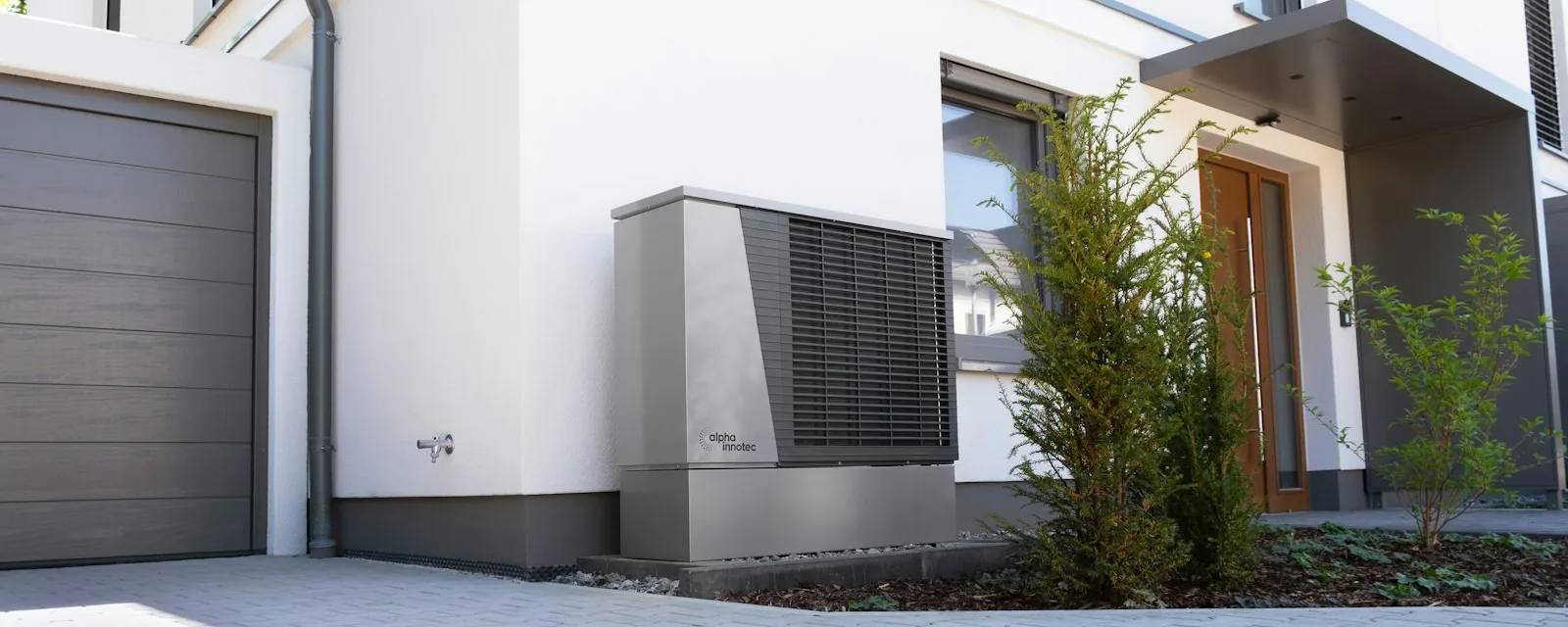 Modern house exterior with an outdoor heat pump / AC unit beside the garage