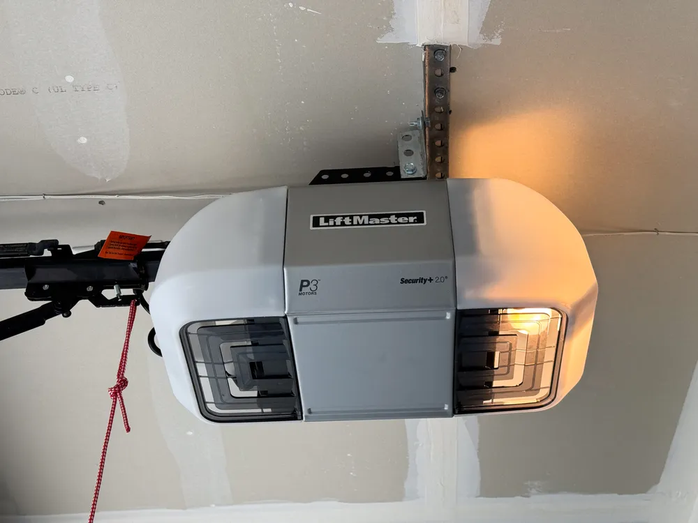 Ceiling-mounted garage door opener motor unit with its rail and red emergency release cord