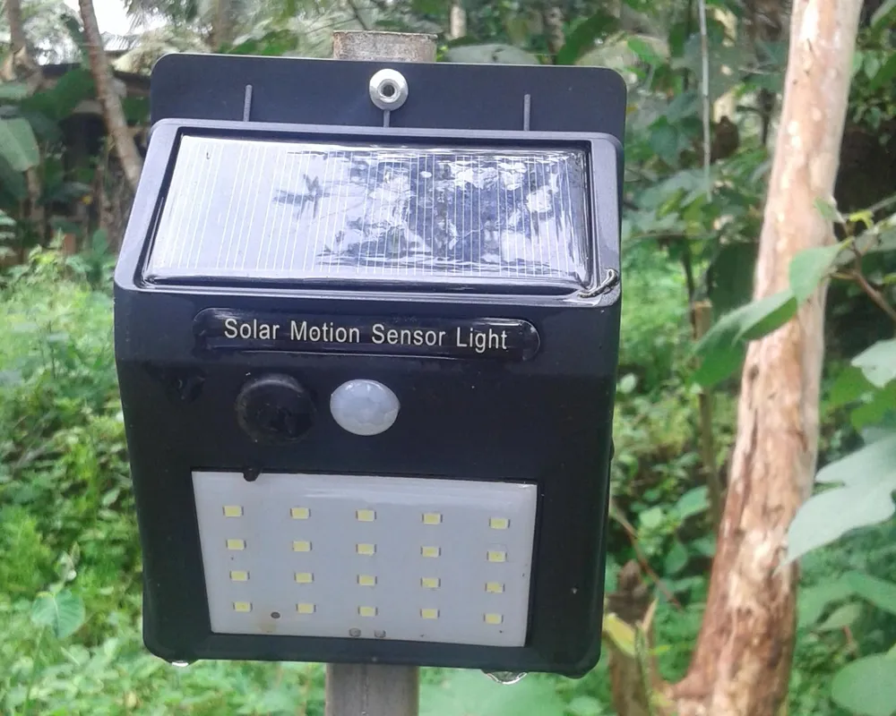 Solar motion sensor light with a top solar panel, PIR sensor and LED panel mounted on a post outdoors